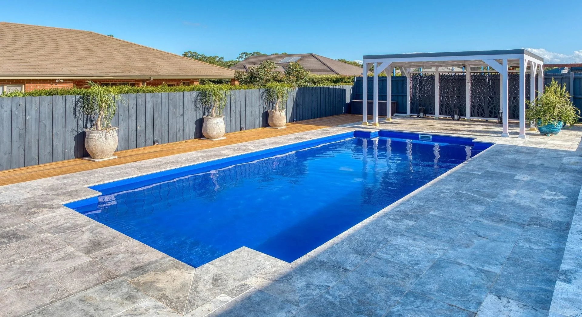 Classic swimming pool with dark blue water beside an outdoor pavilion